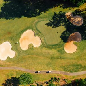 green golf course with bunkers near wavy road