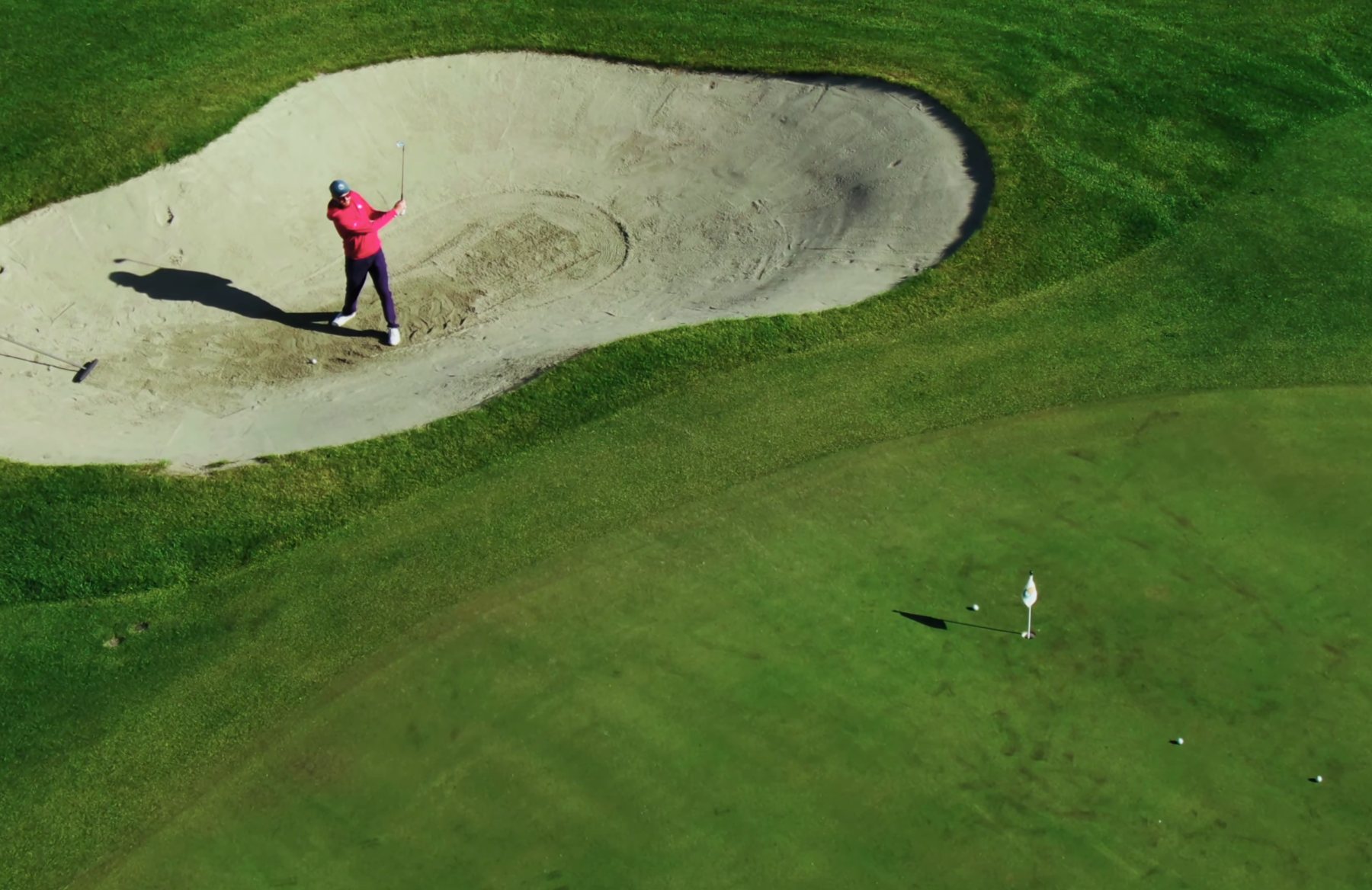 Spiller slår bunkerslag mot green på treningsfeltet